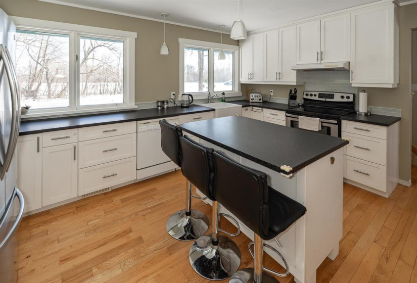 Spacious eat-in kitchen with white farmhouse sink and island with breakfast bar. Lovely wood floors!