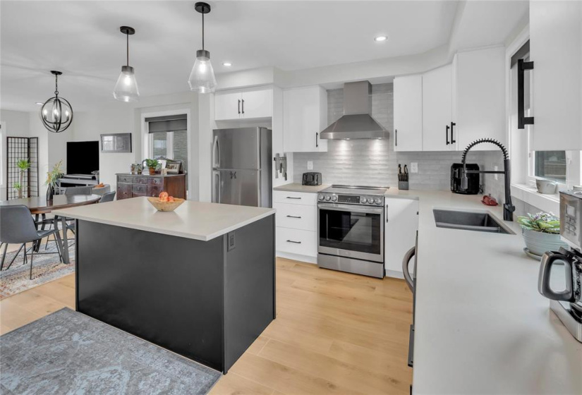 2 hanging pendent lights over the island. Chimney style exhaust fan & high end slide in range. Black sil-granite undermount Kit sink. S.S. fridge. Commercial style black faucet.