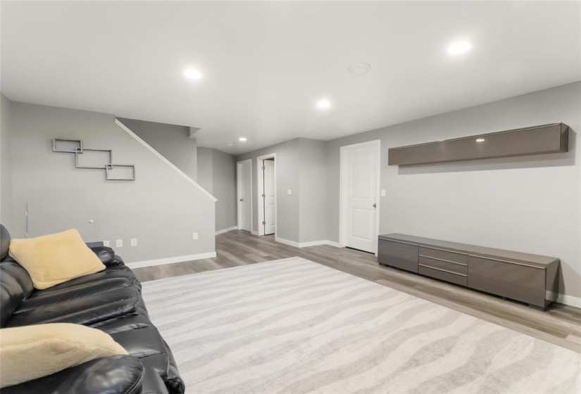 Rec room with door to storage room.  Entertainment unit and shelf included. Shelves in storage room included.