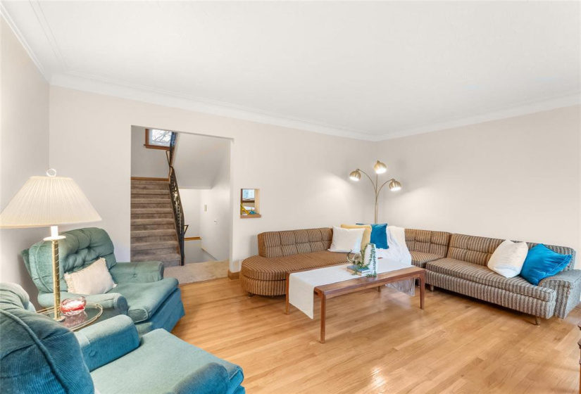 Bright spacious living room with original hardwoods, coved ceiling and new front window.