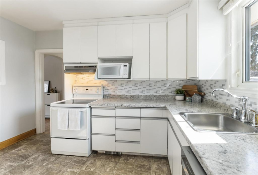 Bright white kitchen. Fridge, stove, hoodfan, microwave and dishwasher included