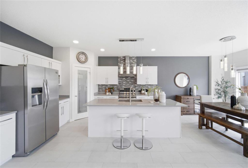 Sophisticated culinary space boasting a full suite of stainless steel appliances, dedicated bar fridge and expansive quartz countertops complemented by your walk-through pantry.