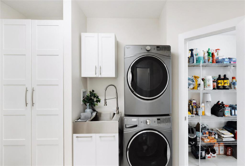 Streamlined utility mudroom featuring integrated washer and dryer, custom cabinetry and a deep utility sink wioth access your walk-through pantry
