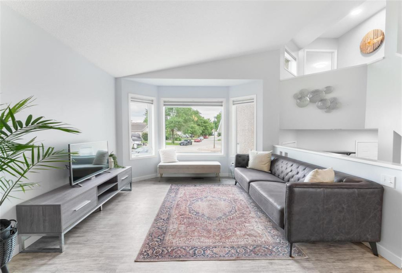 Living room with vaulted ceiling, large window to let in natural light